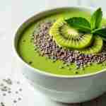 Ricette con spirulina: scopri segreti nutritivi irresistibili: "Un'elegante ciotola di smoothie verde brillante con spirulina, decorata con fette di kiwi, semi di chia e foglie di menta, su uno sfondo di legno chiaro."